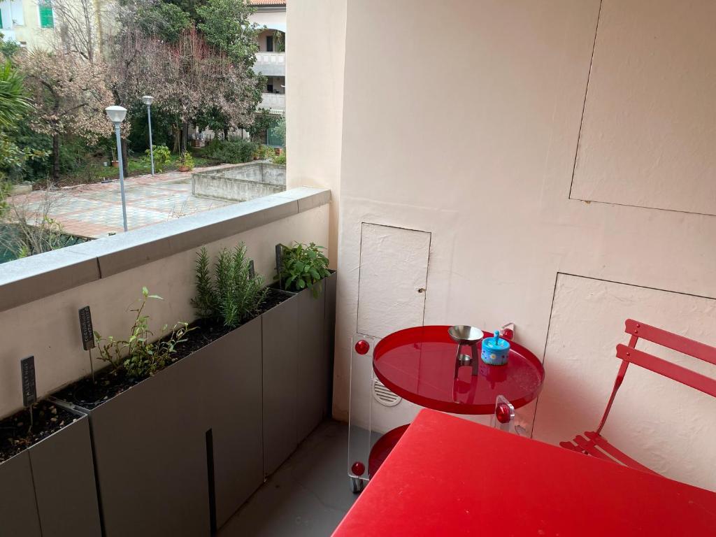 Balcone con piante aromatiche e tavolino rosso